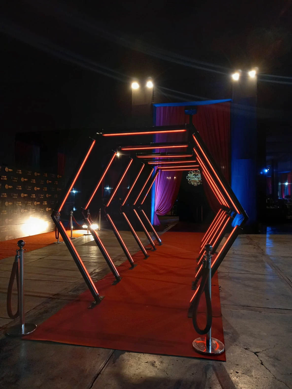 Túnel LED hexagonal rojo: Entrada impactante sobre alfombra roja, perfecta para eventos de gala y celebraciones. - Túnel hexagonal led - scratch perú.