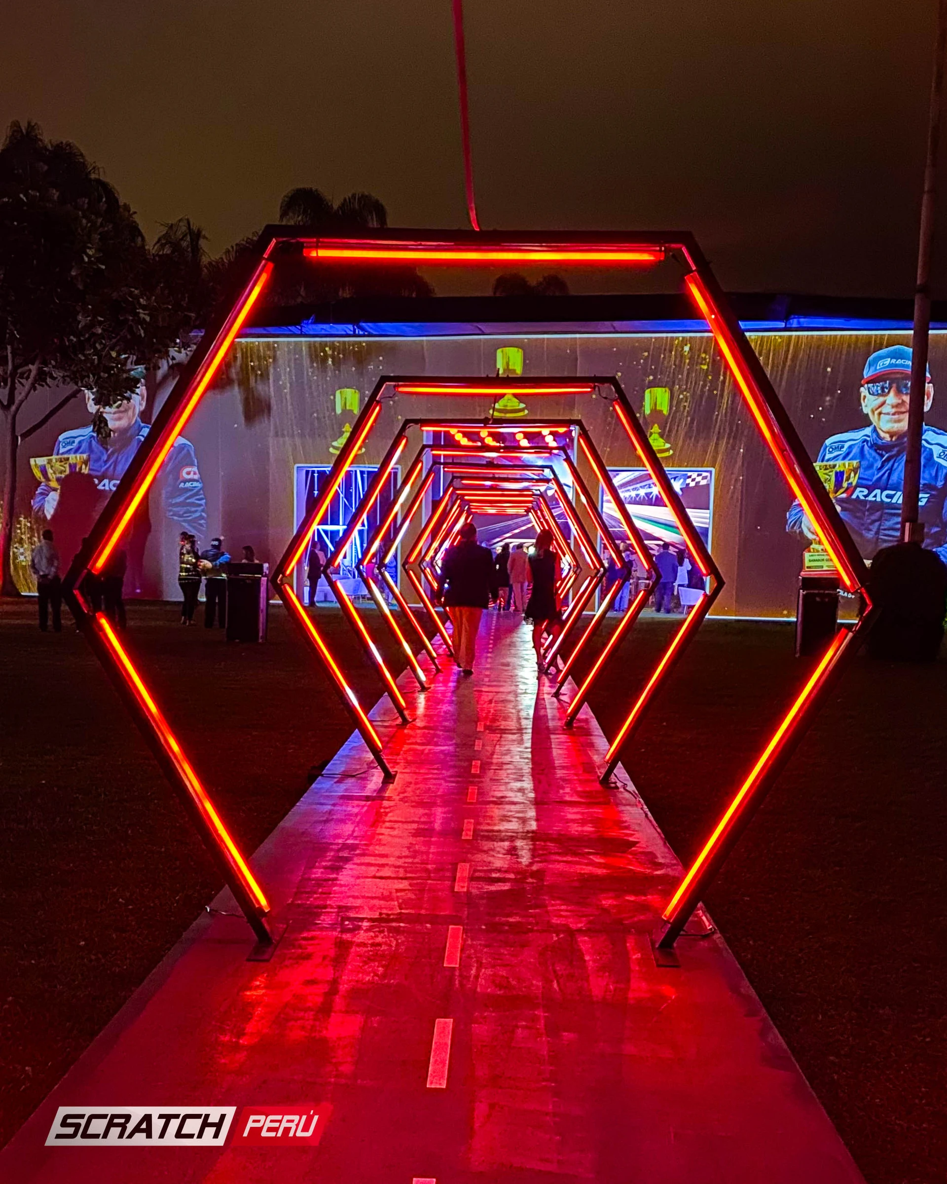 Túnel LED hexagonal rojo: Entrada dramática con personas ingresando al evento, capturando momentos memorables. - Túnel hexagonal led - scratch perú.