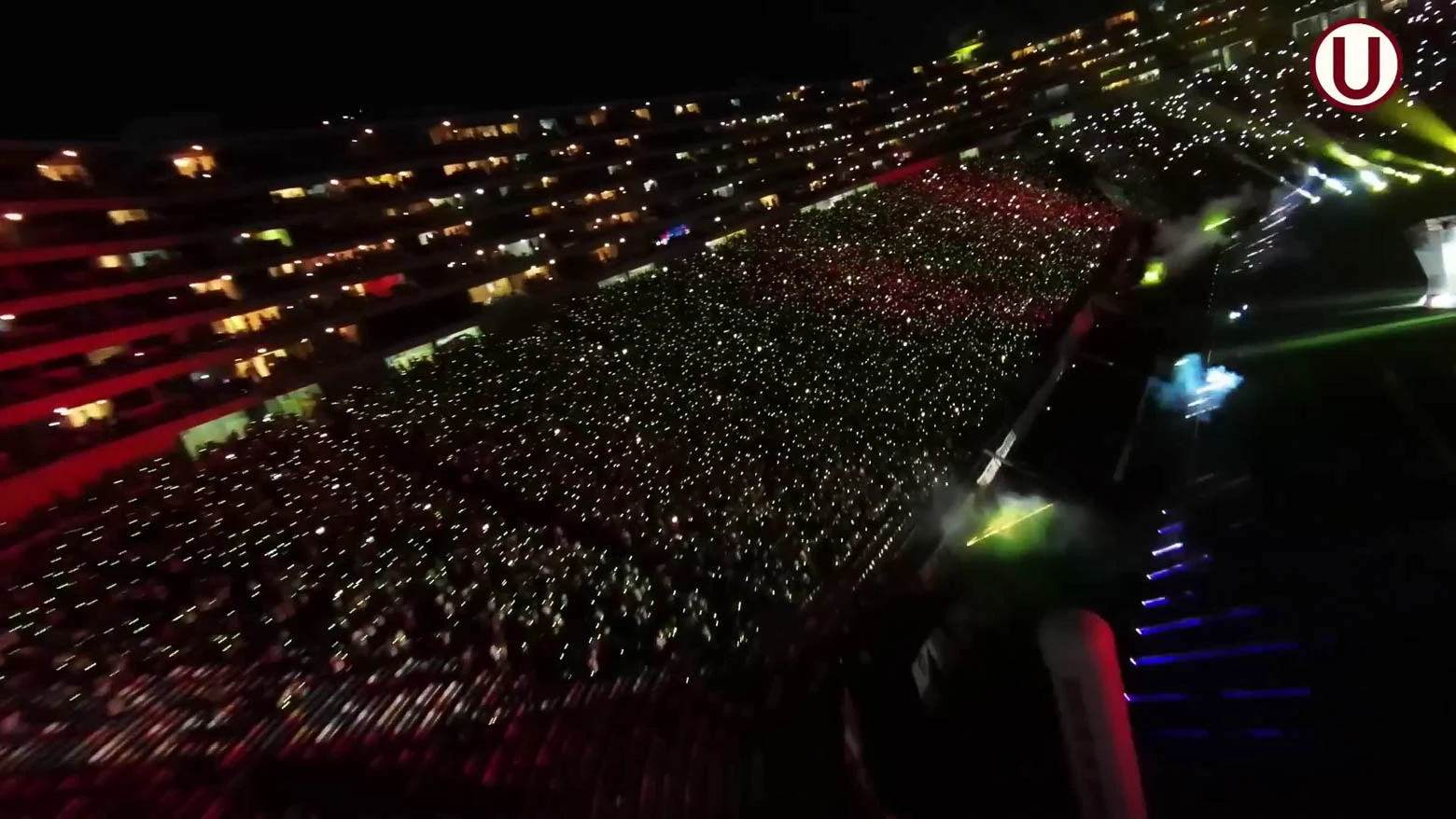 Vista panorámica de un estadio de fútbol lleno de espectadores que llevan pulseras LED DMX inalámbricas de diferentes colores, controladas en tiempo real para crear efectos visuales impresionantes - Iluminación espectacular en Noche Crema 2024 con Scratch Perú - scratch perú.