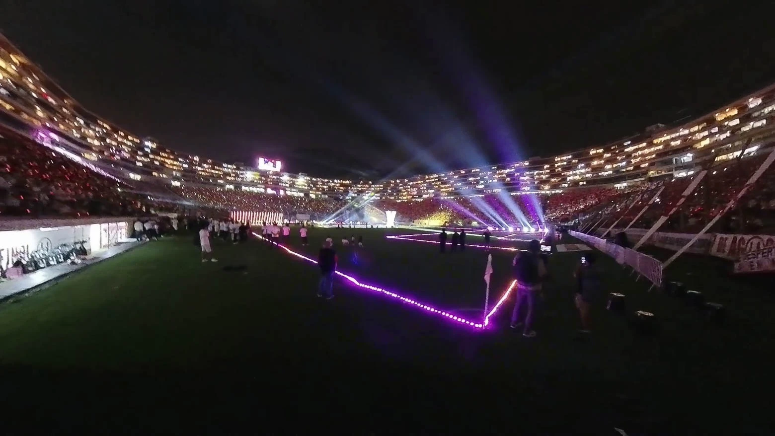 Vista aérea del Estadio Monumental de Lima desde un dron con fuegos artificiales y 40,000 espectadores, con el campo y las gradas iluminados por mini píxeles y túneles de tubos LED, que crean un espectáculo de luz y color - Iluminación espectacular en Noche Crema 2024 con Scratch Perú - scratch perú.