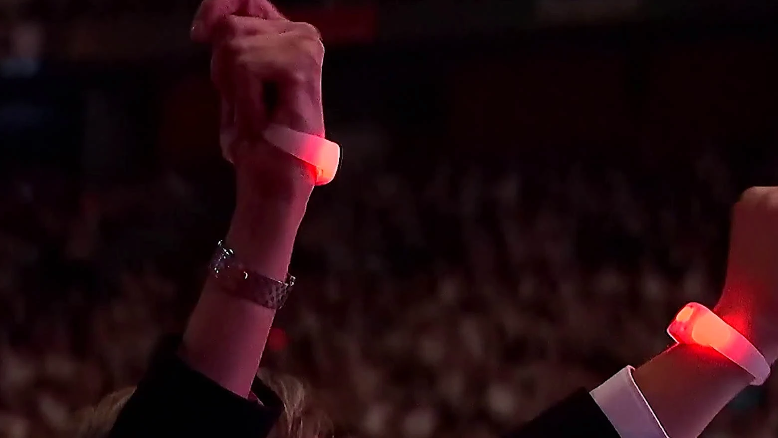 Vista desde la entrada del estadio de una mujer colocándose un brazalete luminoso al ingresar al evento en el estadio, con el brazalete mostrando el logo del evento y el color del equipo que apoya - Iluminación espectacular en Noche Crema 2024 con Scratch Perú - scratch perú.