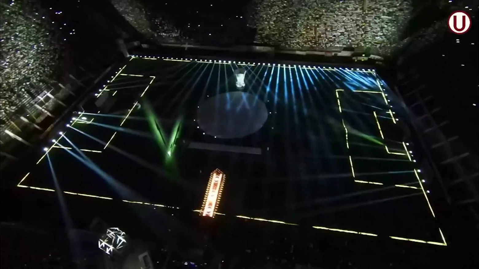 Vista aérea de un estadio de fútbol captada desde un dron, con el campo y las gradas iluminados por mini píxeles y túneles de tubos LED, que crean un espectáculo de luz y color - Iluminación espectacular en Noche Crema 2024 con Scratch Perú - scratch perú.
