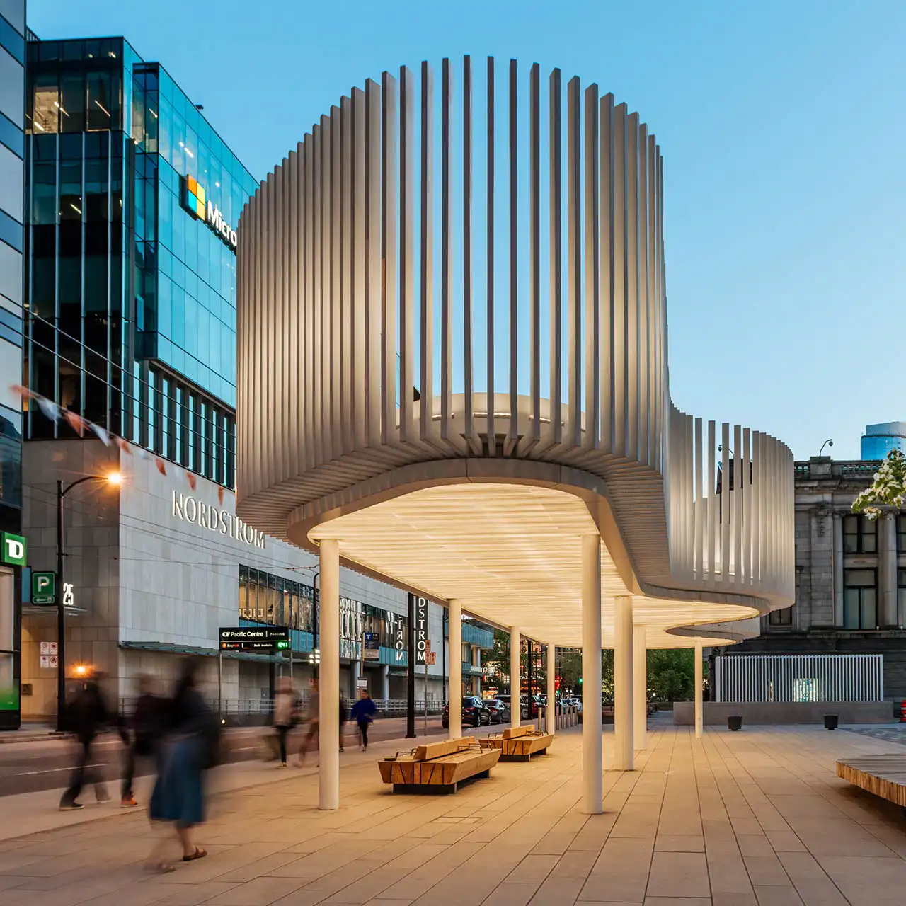 Estructura arquitectónica moderna iluminada con luces LED en una plaza urbana, destacando un diseño curvo y vanguardista con efectos de luz cálida. Ideal para espacios públicos y eventos.