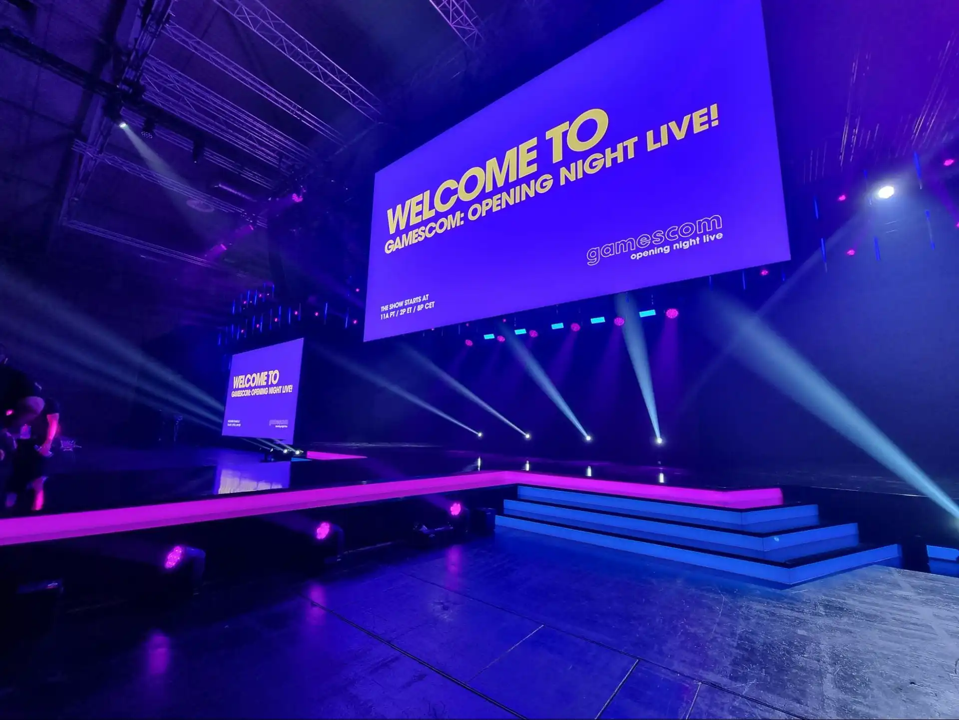 Escenario principal de Gamescom con pantallas LED gigantes, ofreciendo una visualización espectacular de las presentaciones. La iluminación y el diseño del escenario complementan la alta resolución de las pantallas.