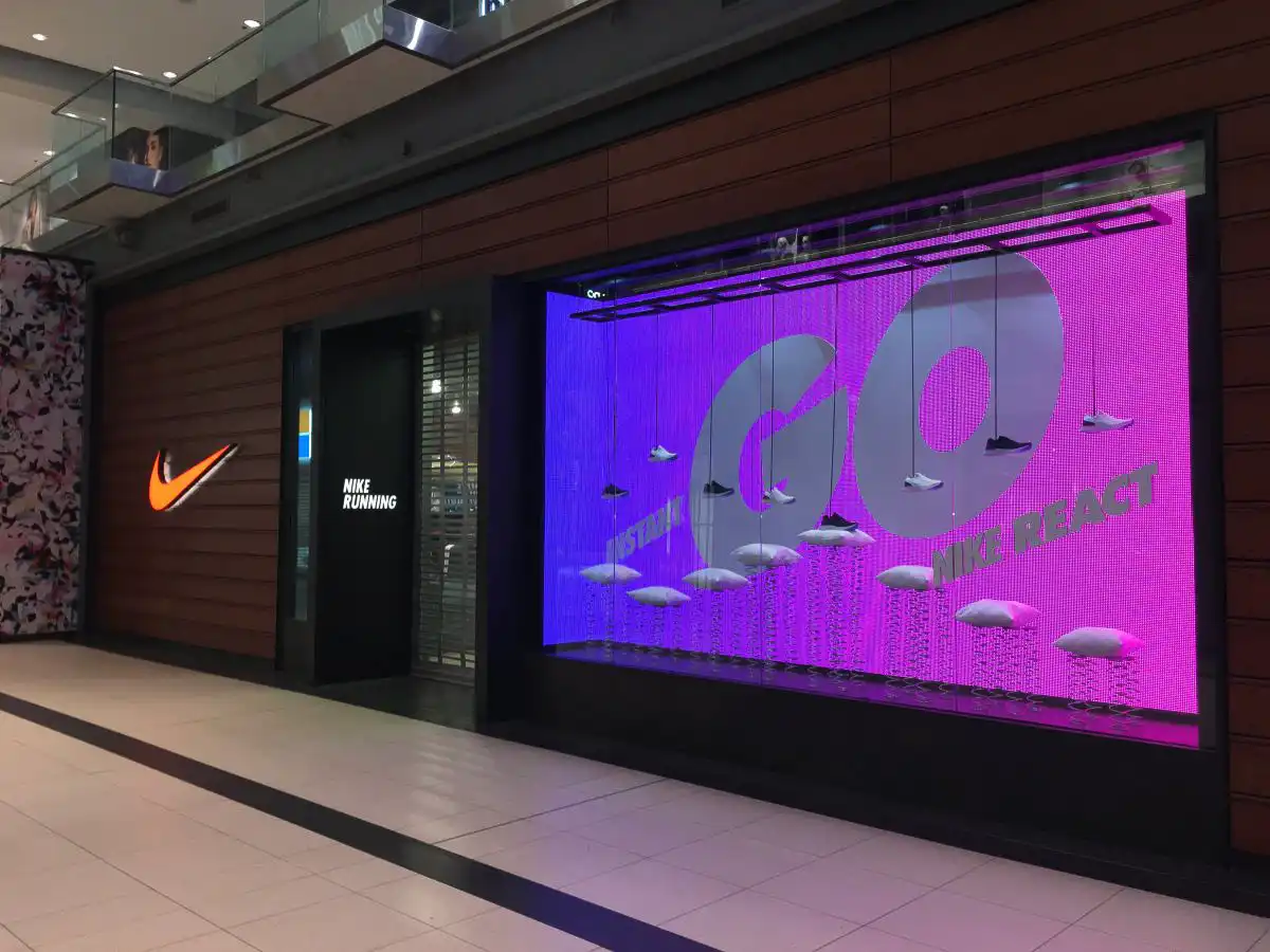 Pantalla LED en el escaparate de una tienda Nike, mostrando contenido interactivo y promocional que atrae a los clientes y destaca la innovación de la marca.