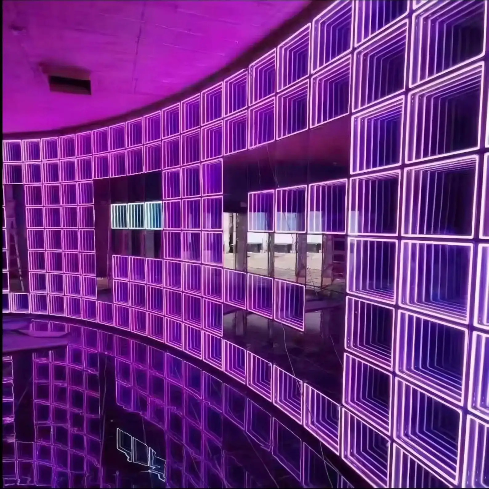 Vista panorámica del muro curvo de paneles LED Espejo Infinito 3D púrpura Segunda vista del muro curvo de paneles LED Espejo Infinito 3D en tono púrpura, mostrando la continuidad del efecto de túnel infinito en todo el perímetro.
