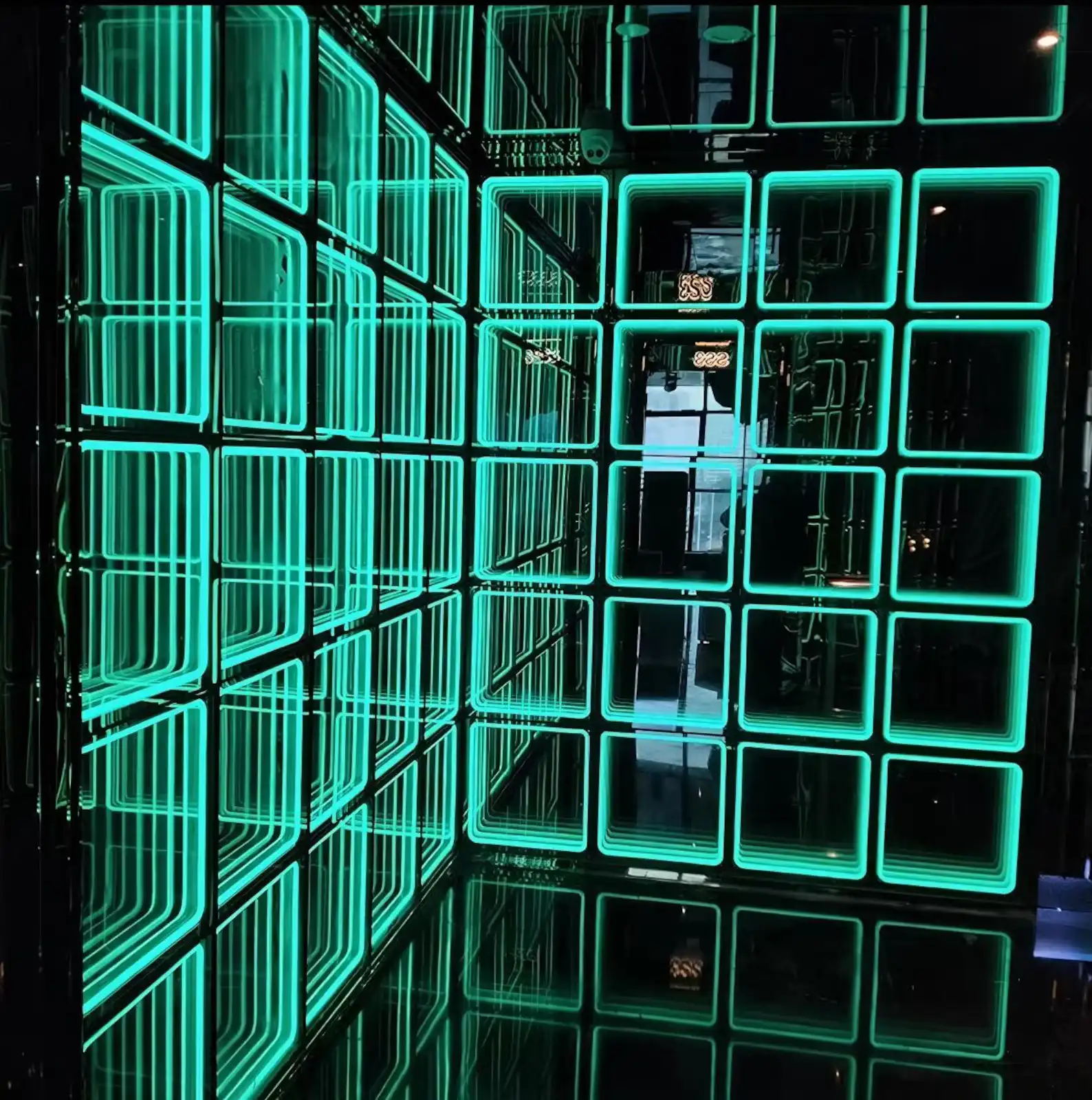 Detalle de esquina con paneles LED Espejo Infinito 3D en tono turquesa Vista de detalle de una esquina revestida con paneles LED Espejo Infinito 3D en tono turquesa, mostrando el efecto de túnel infinito en dos planos.