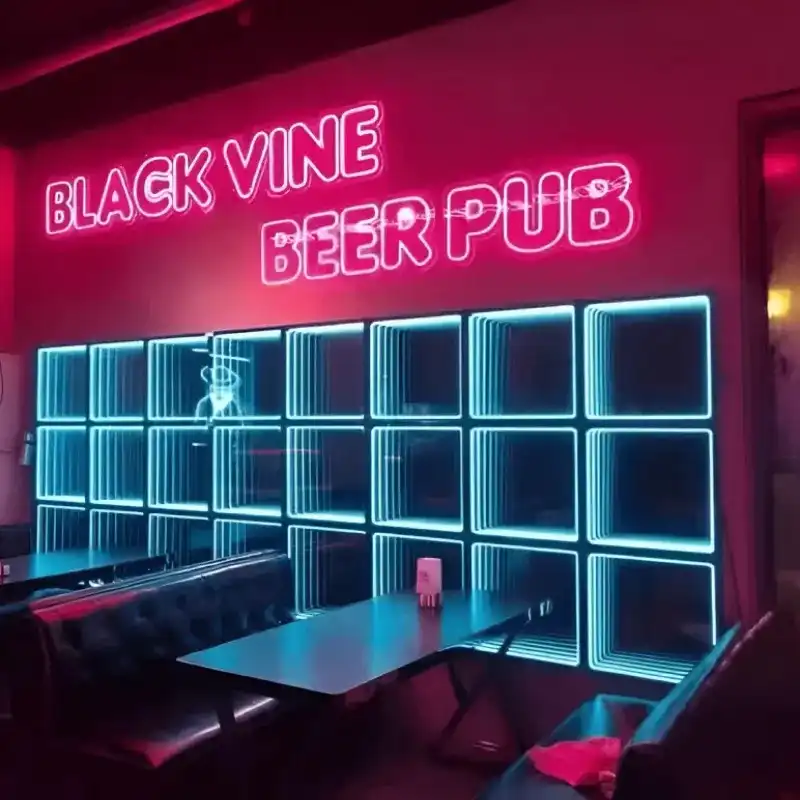 Pared LED Espejo Infinito 3D en un pub junto al letrero Black Vine Beer Pub Pared de paneles LED Espejo Infinito 3D en tono turquesa instalada bajo el letrero de neón Black Vine Beer Pub, en un ambiente de pub con sillones de cuero.
