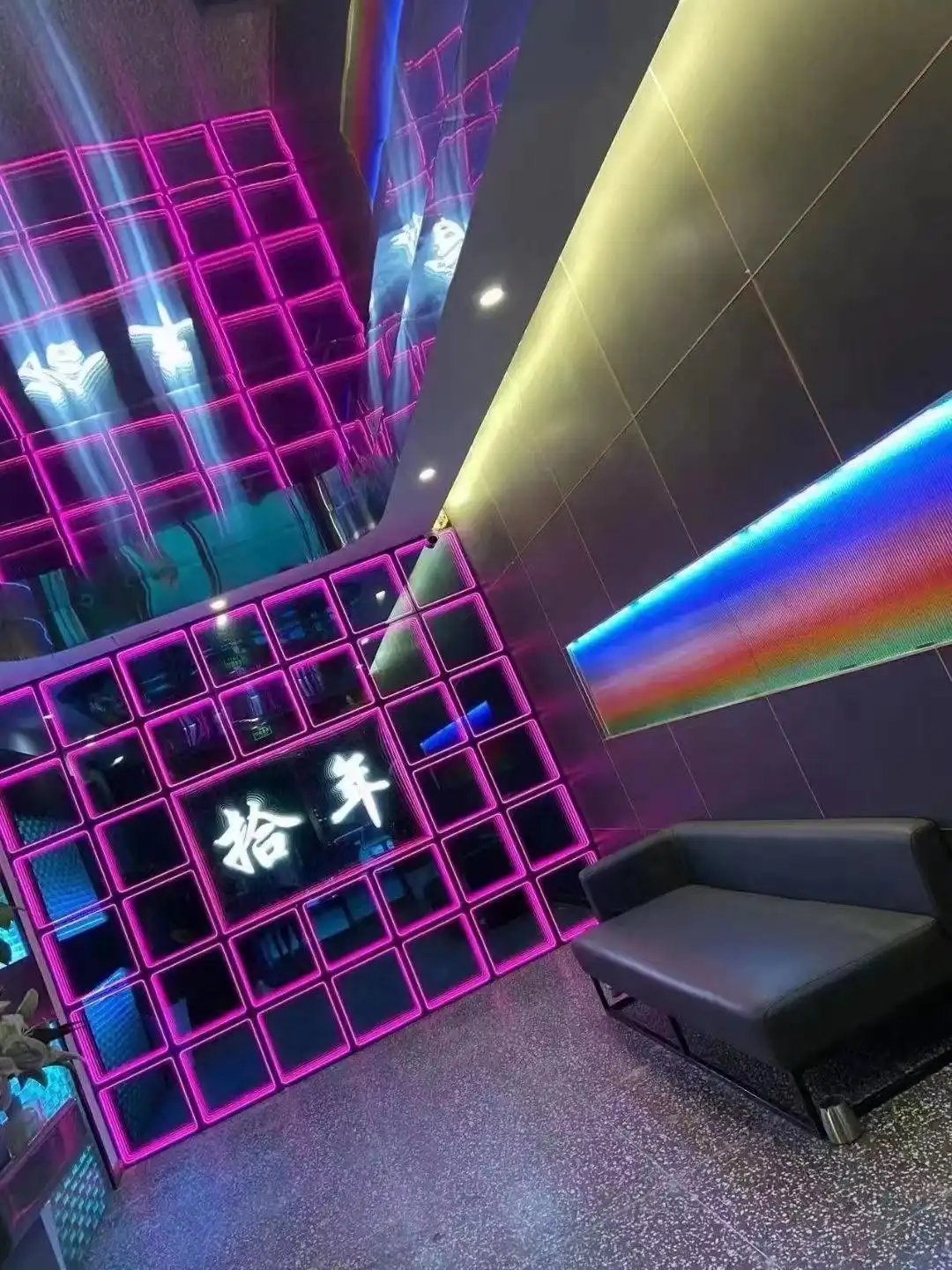 Pared LED Espejo Infinito 3D en tono fucsia con texto decorativo Muro de paneles LED Espejo Infinito 3D en color fucsia con caracteres decorativos iluminados y reflejo de una franja arcoíris en el ambiente.