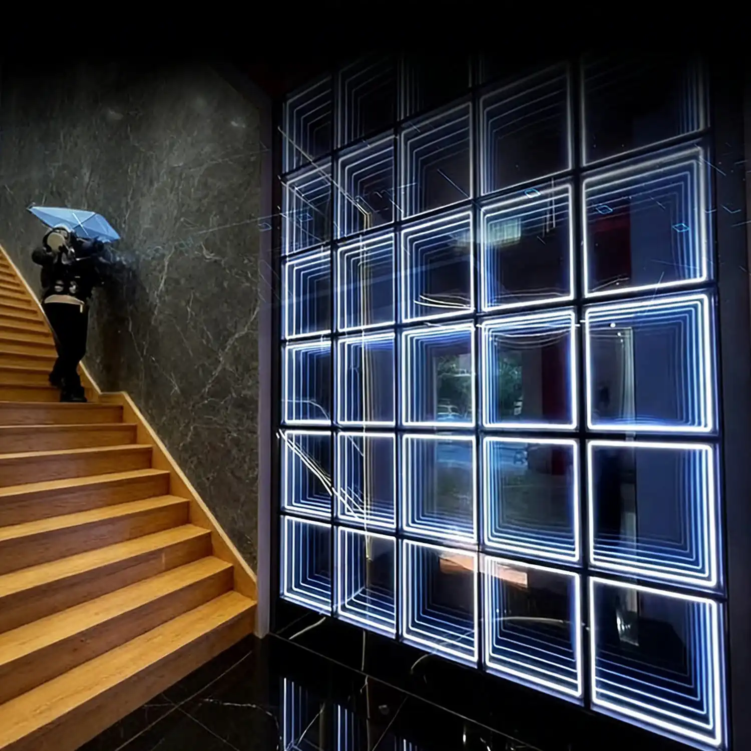 Muro de paneles LED Espejo Infinito 3D en tono azul blanco junto a una escalera de madera, con un técnico instalando el sistema.