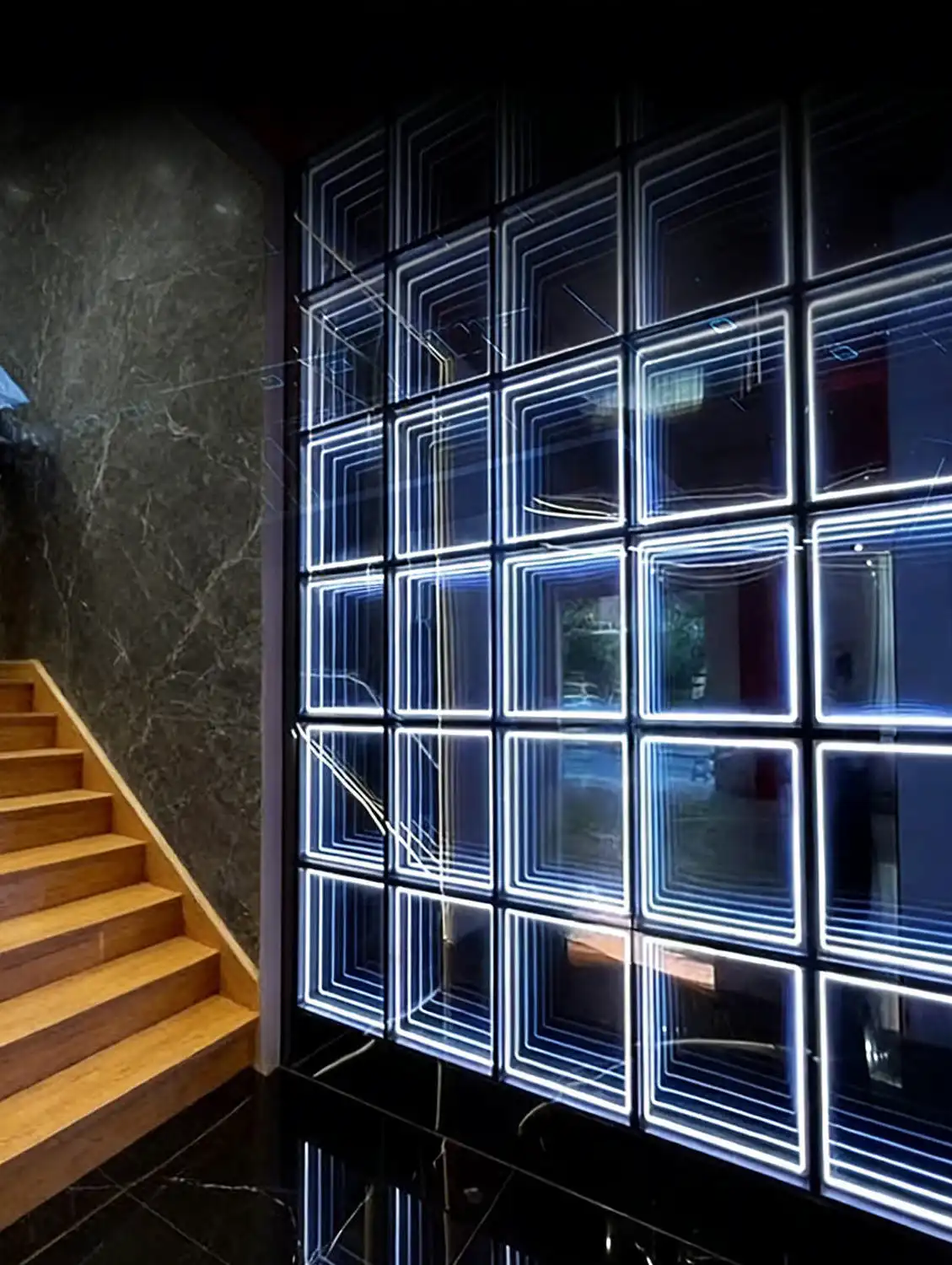 Panel LED Espejo Infinito 3D 50x50 cm RGB tarjeta de catálogo Pared de paneles LED Espejo Infinito 3D en tono azul blanco junto a una escalera de madera, imagen representativa del producto para el catálogo.