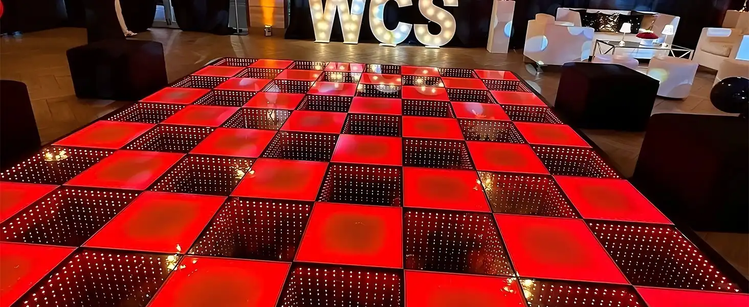 Pista LED 3D Infinity Mirror roja junto al letrero luminoso WCS Pista de baile LED 3D Infinity Mirror en tono rojo instalada en un lounge privado junto al letrero luminoso WCS y sofás oscuros.