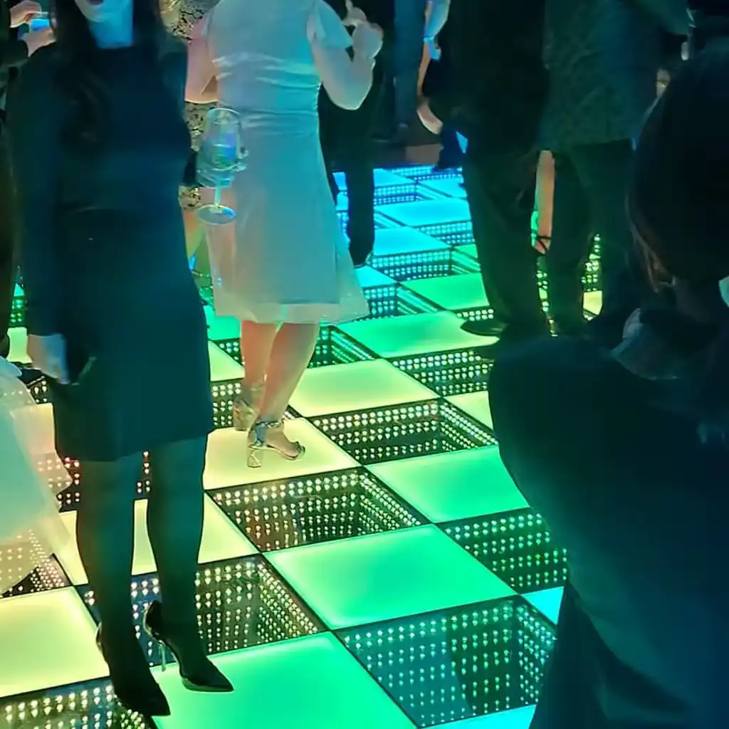 Invitada bailando sobre la pista LED 3D Infinity Mirror verde en una fiesta Invitados bailando en movimiento sobre la pista de baile LED 3D Infinity Mirror en tono verde durante una celebración.