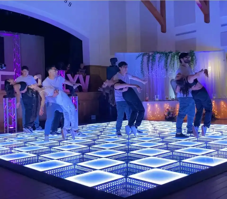 Grupo de baile coreografiado sobre la pista LED 3D Infinity Mirror en una quinceañera Bailarines realizando una coreografía sobre la pista de baile LED 3D Infinity Mirror en tono blanco y azul durante una fiesta de quince años.