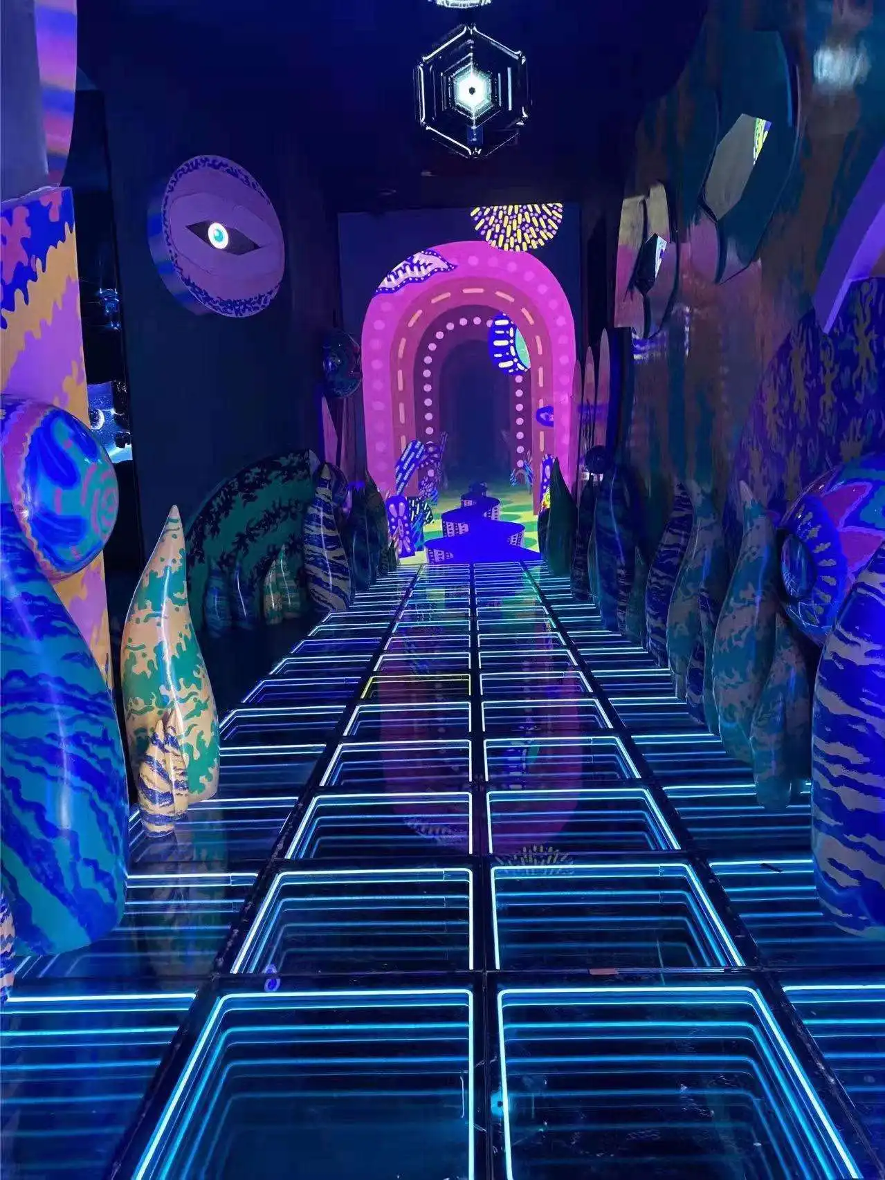 Instalación artística de neón junto a la pista LED 3D Infinity Mirror Pasillo decorado con arte de neón y esculturas coloridas junto a la pista de baile LED 3D Infinity Mirror, creando un ambiente psicodélico.
