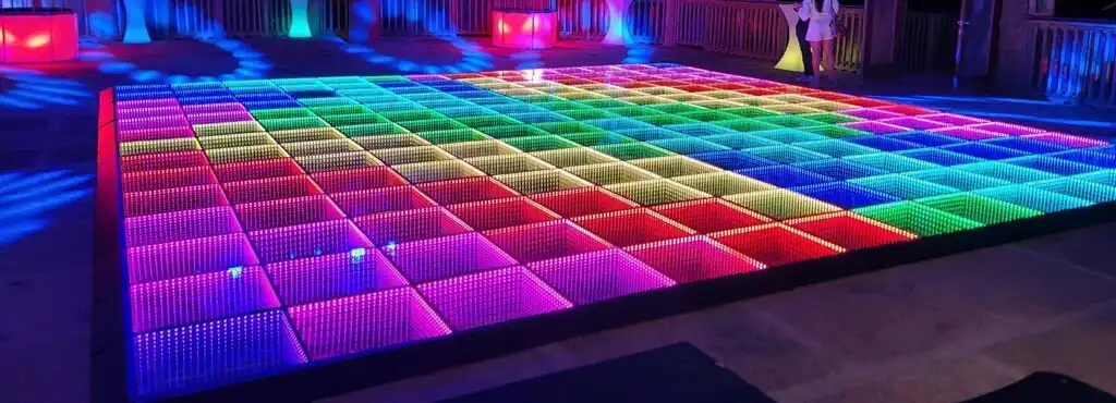 Vista panorámica de la pista LED 3D Infinity Mirror arcoíris en una terraza nocturna Vista panorámica de la pista de baile LED 3D Infinity Mirror en degradado arcoíris instalada en una terraza nocturna al aire libre.