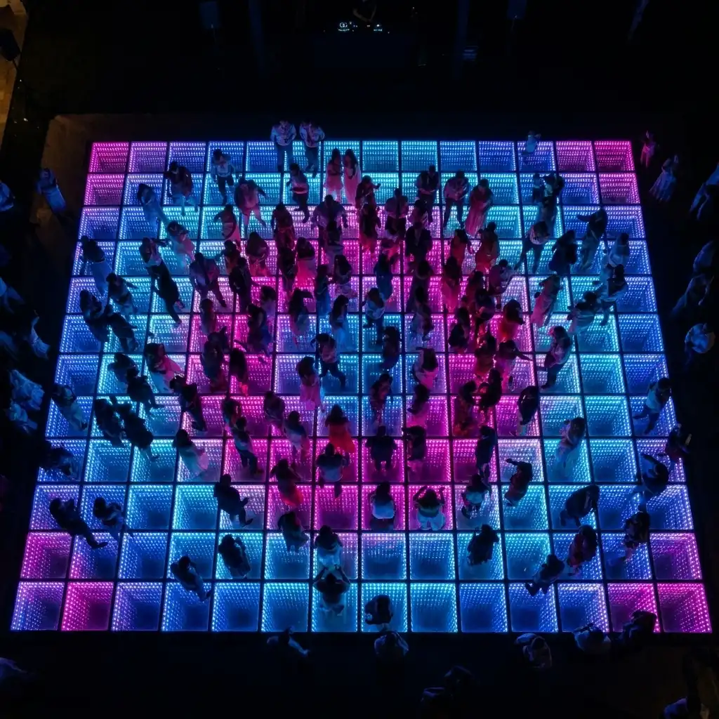 Vista aérea de invitados bailando sobre la pista LED 3D Infinity Mirror Vista aérea de decenas de invitados bailando sobre la pista de baile LED 3D Infinity Mirror en tonos rosa y azul durante una fiesta.