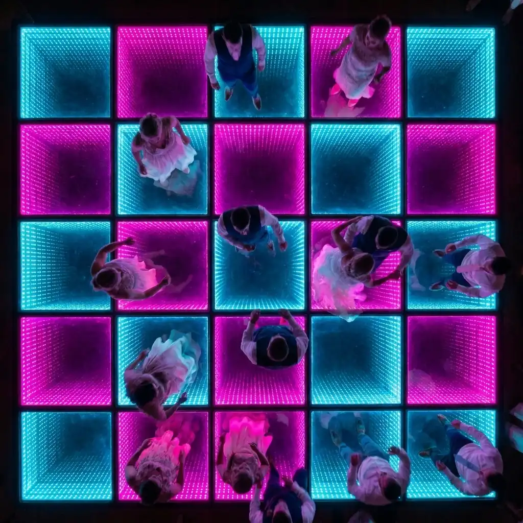 Vista aérea de grupos bailando sobre la pista LED 3D Infinity Mirror Vista aérea de pequeños grupos de invitados bailando sobre la pista de baile LED 3D Infinity Mirror en tonos rosa y azul.