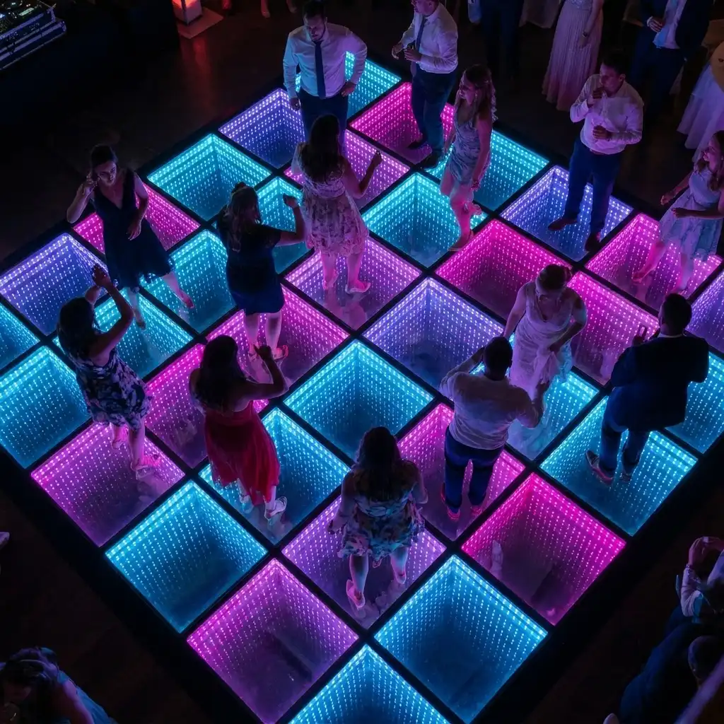 Vista aérea de invitados de gala bailando sobre la pista LED 3D Infinity Mirror Vista aérea de invitados vestidos de gala bailando sobre la pista de baile LED 3D Infinity Mirror en tonos rosa, azul y púrpura.
