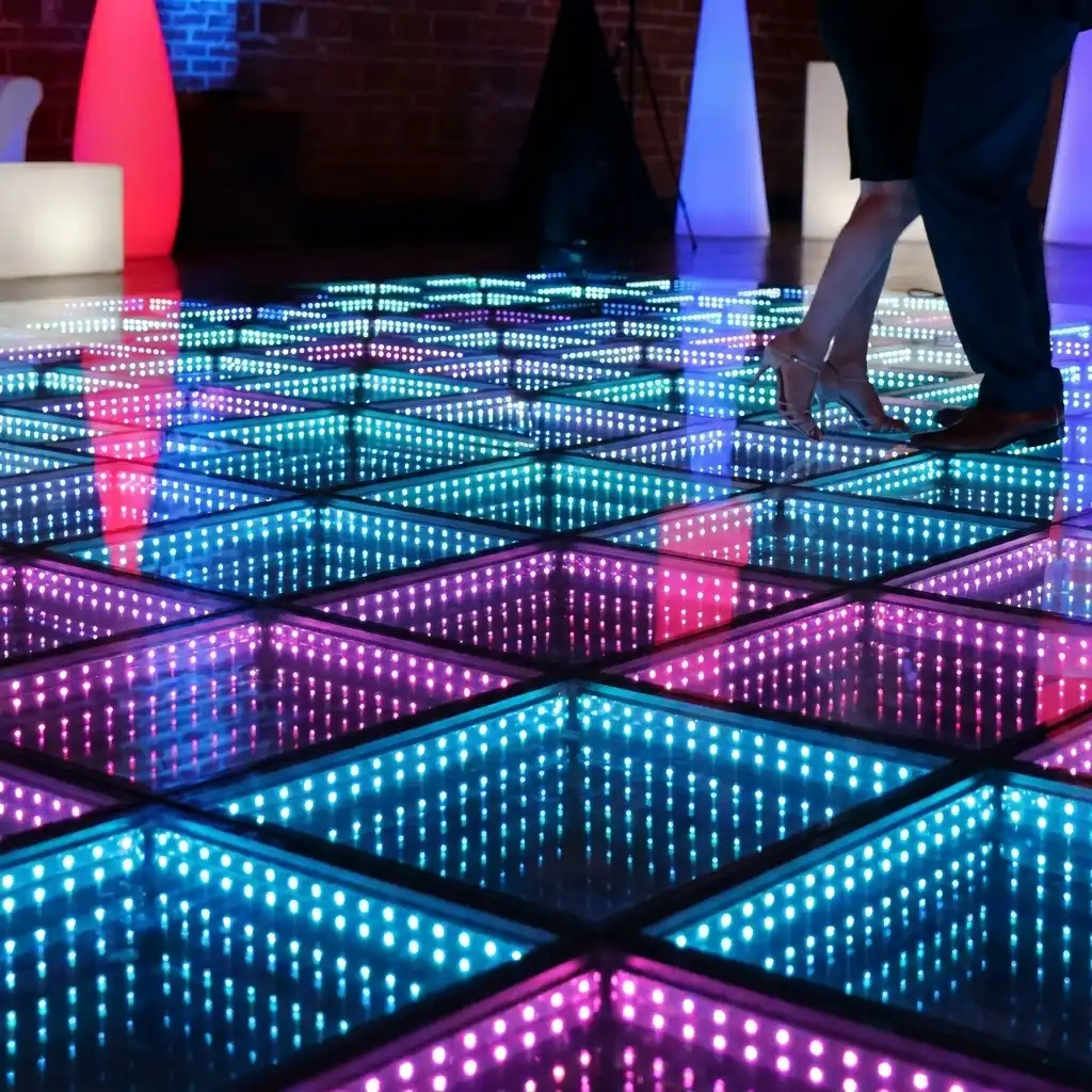 Pareja bailando sobre la pista LED 3D Infinity Mirror en tonos turquesa y púrpura Detalle de una pareja bailando con tacones sobre la pista de baile LED 3D Infinity Mirror en tonos turquesa y púrpura.