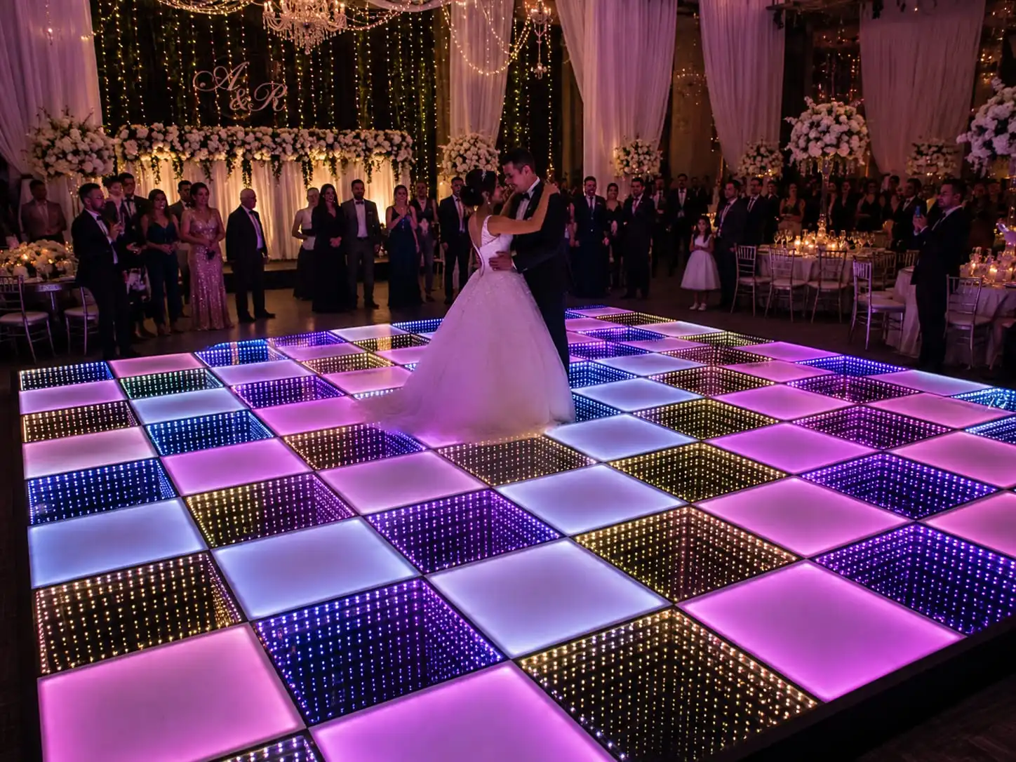 Segundo ángulo del primer baile de los novios sobre la pista LED 3D Infinity Mirror Los novios bailando frente a sus invitados sobre la pista de baile LED 3D Infinity Mirror con el monograma A&R y cortinas de luces al fondo.
