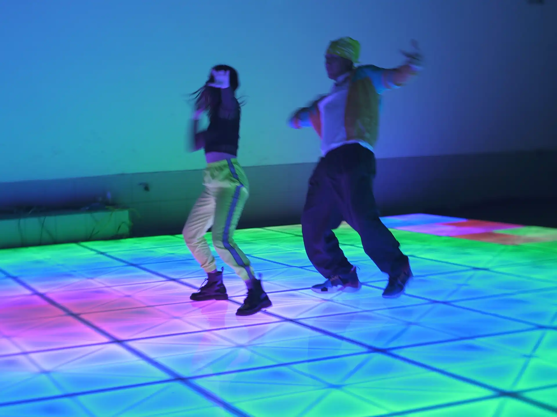 Pareja bailando en una pista de baile LED iluminada en tonos azul y púrpura, creando un ambiente dinámico y vibrante.