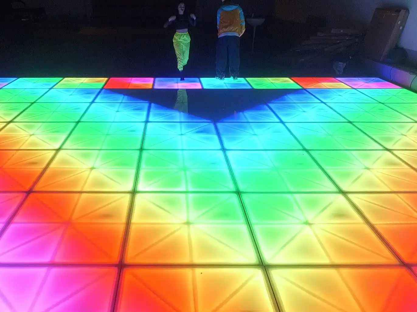 Personas bailando sobre una pista de baile LED RGB con efectos verdes brillantes, ideal para animar reuniones sociales.