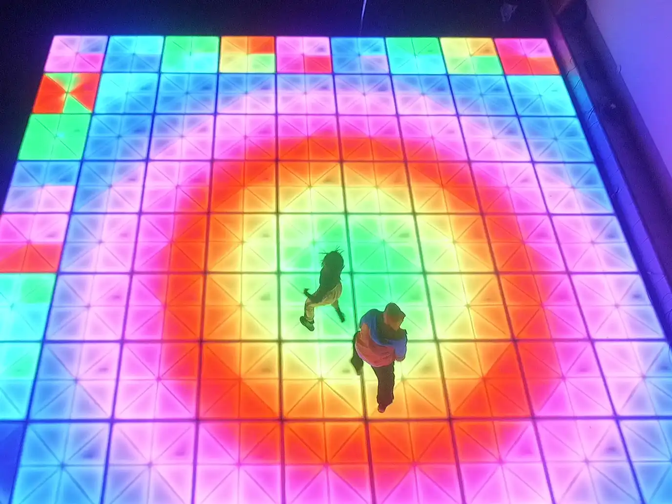 Vista de una pista de baile LED con efectos multicolores en tonos cálidos y fríos, diseñada para eventos grandes.