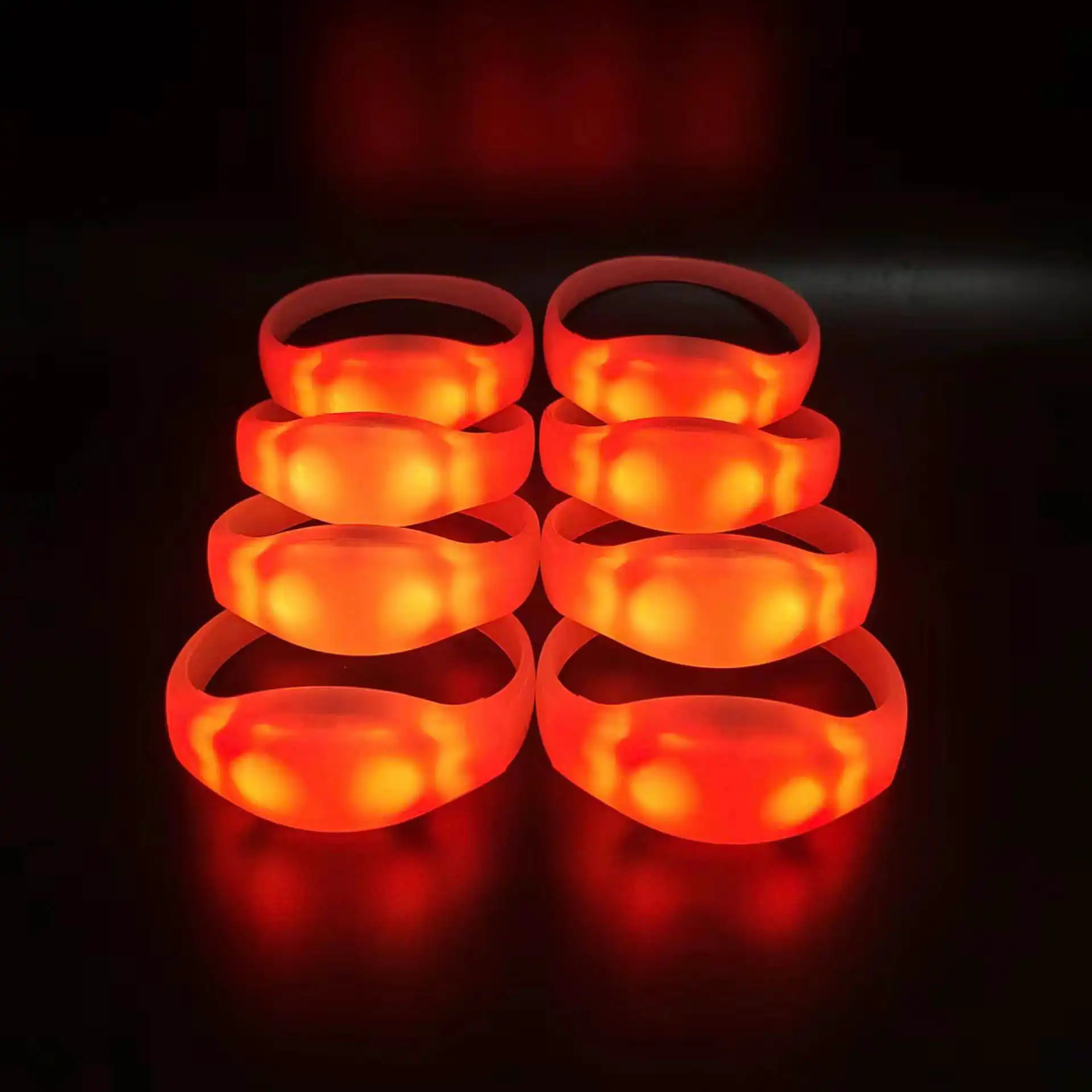 Pulseras LED rojas brillando en grupo, utilizadas en eventos masivos para sincronización y personalización.