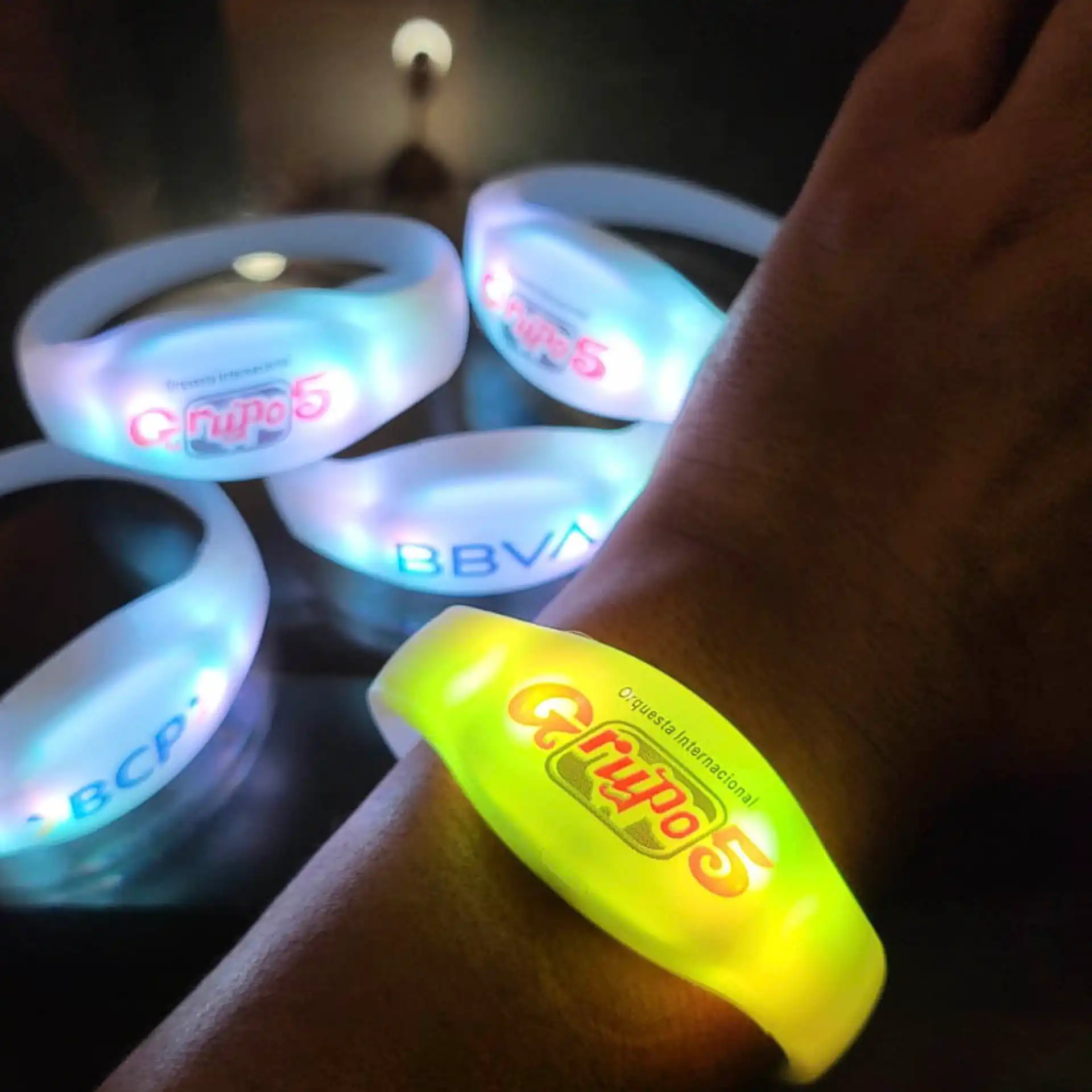 Pulsera LED personalizada para Grupo 5, iluminada en verde y utilizada en un evento para crear una experiencia visual interactiva.