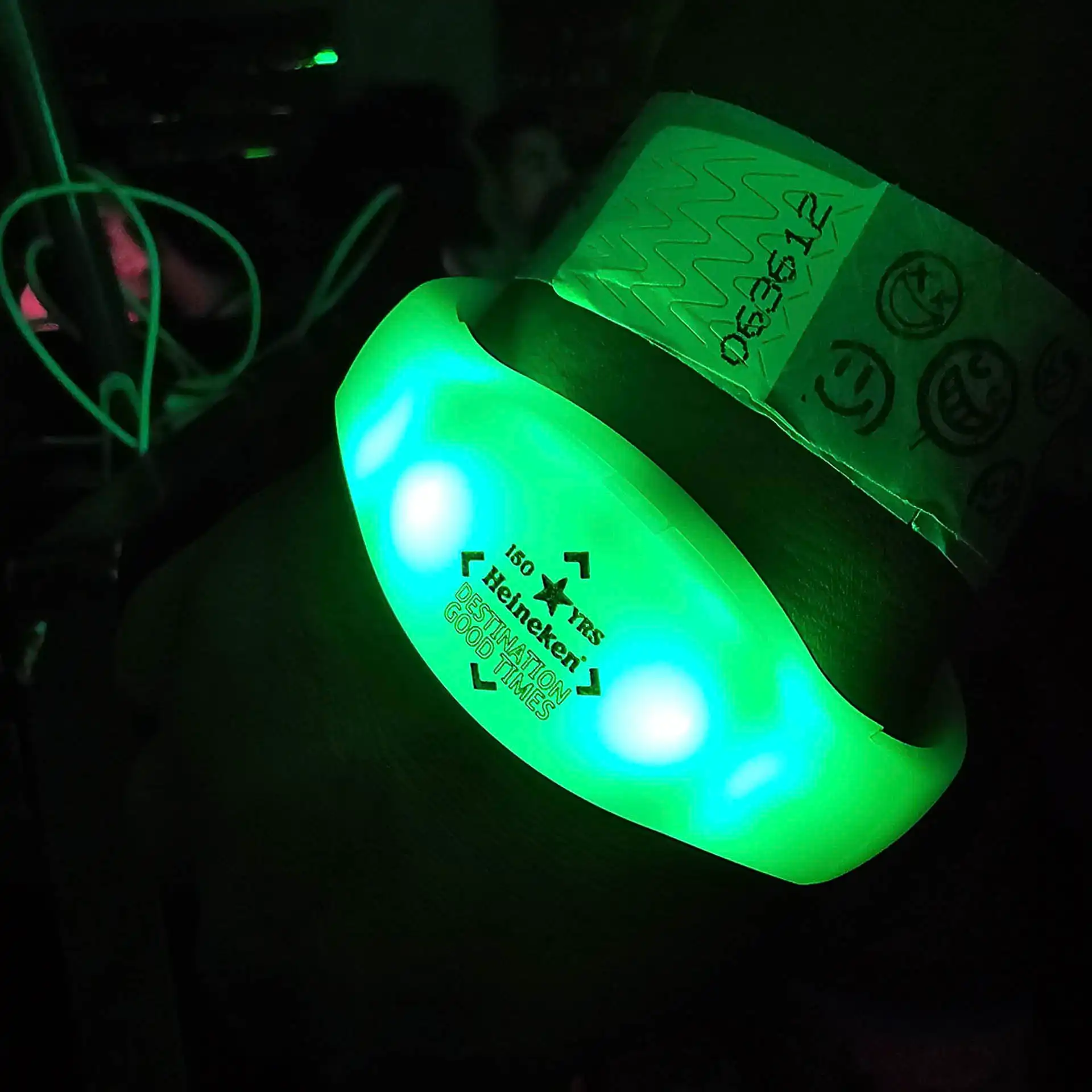 Pulsera LED verde iluminando en un evento nocturno, ideal para personalización y sincronización en espectáculos en vivo.