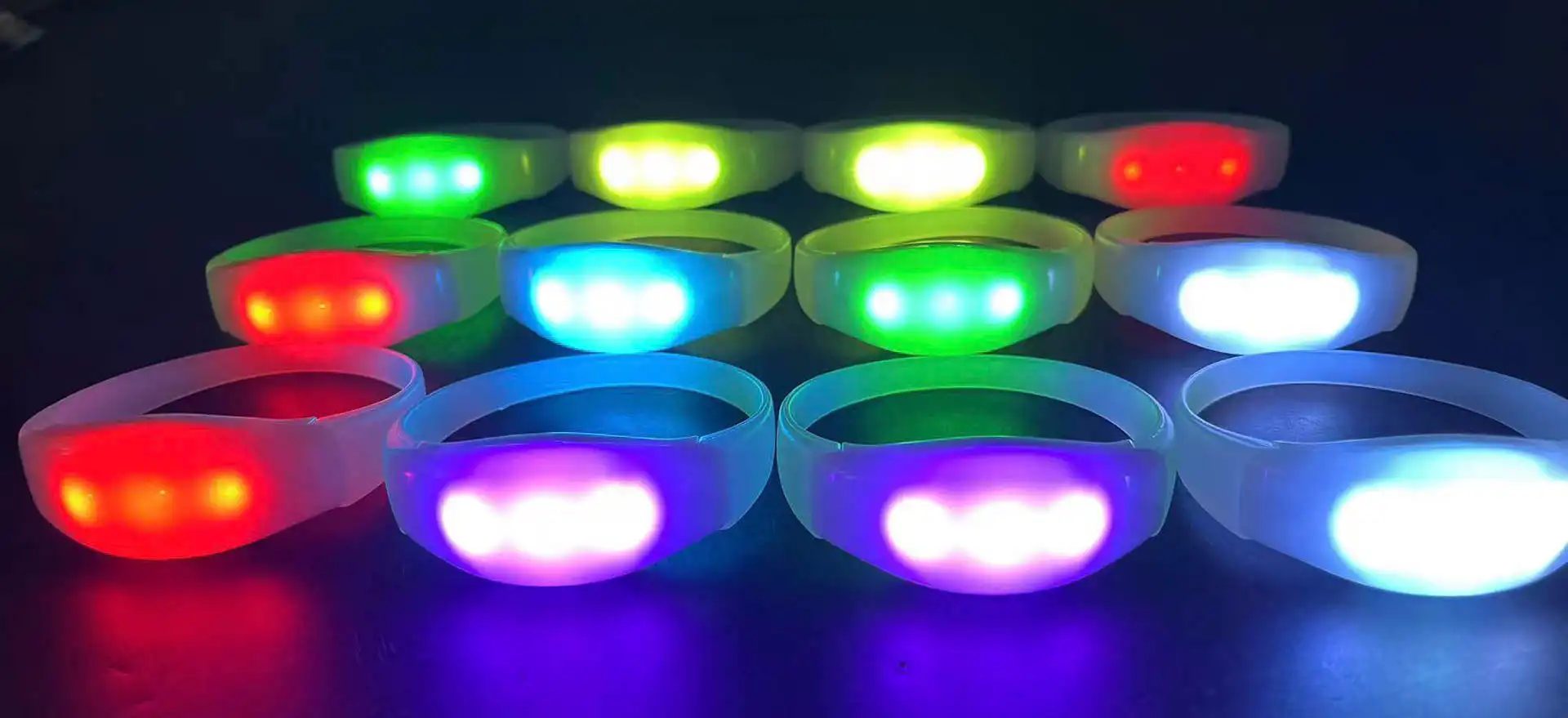 Filas de pulseras LED iluminadas en varios colores, incluyendo verde, rojo, azul y púrpura.