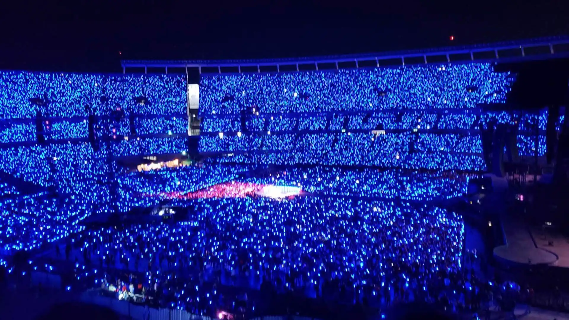 Vista panorámica de un estadio iluminado completamente con luces LED azules durante un concierto.