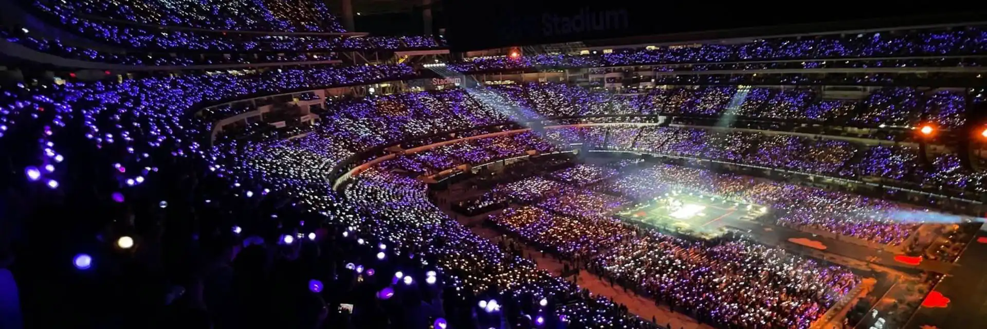 Imagen de un estadio lleno de luces LED en tonos morado y plateado creando una atmósfera vibrante.