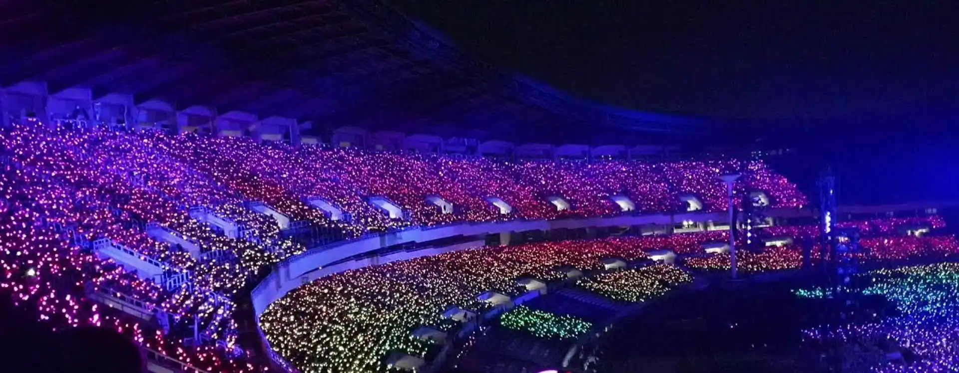 Pulseras LED inalambricas iluminando el estadio en un concierto masivo, creando una atmósfera vibrante y única. Perfectas para grandes eventos como conciertos de Coldplay o Taylor Swift.