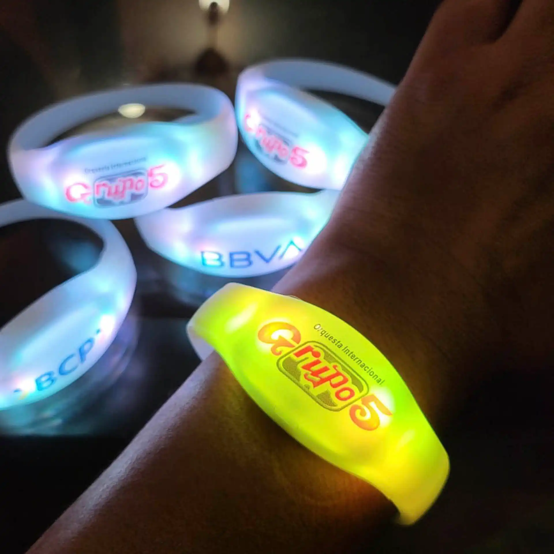 Primer plano de pulseras LED con logotipos personalizados, ideal para branding y promociones en conciertos y festivales masivos.