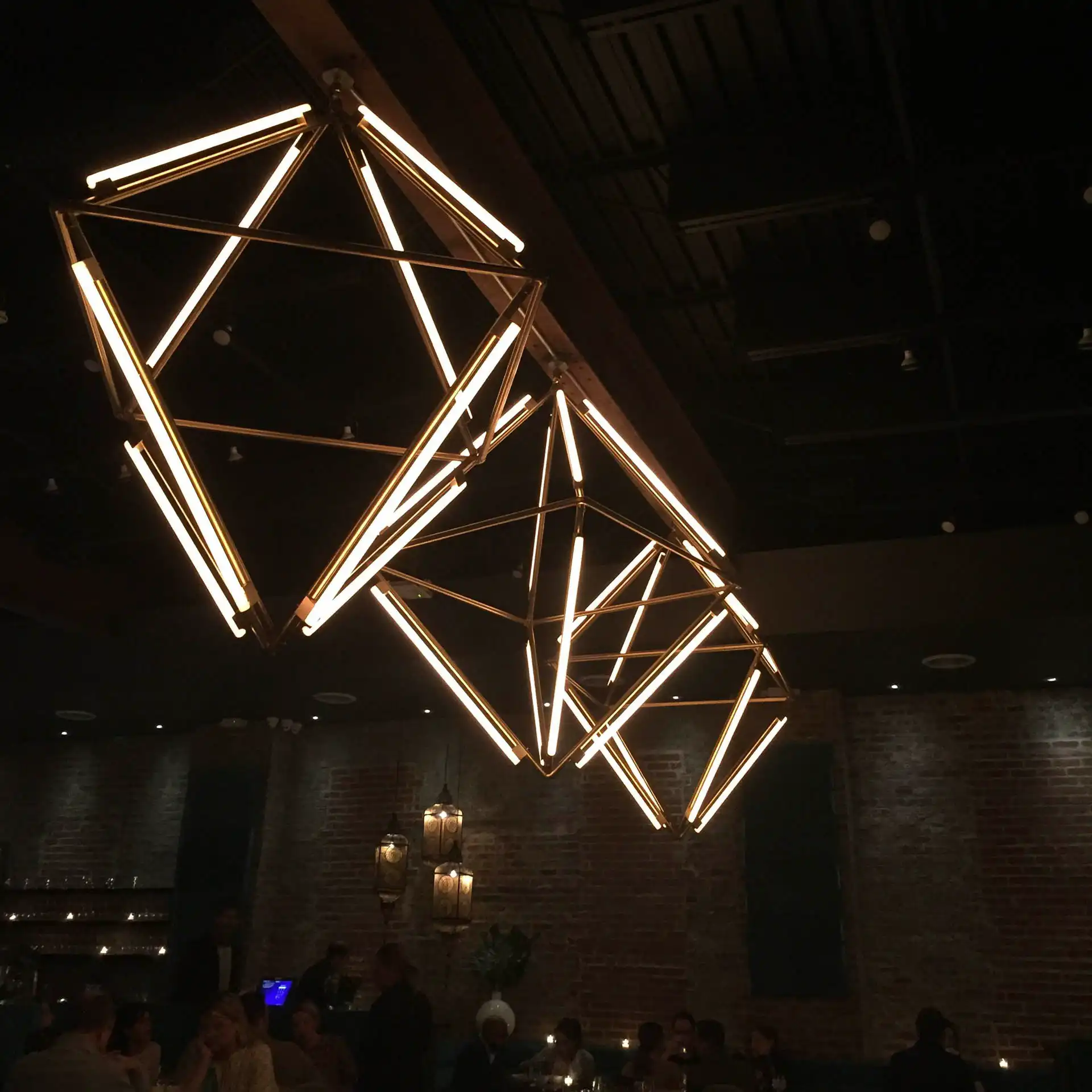 Instalación de iluminación geométrica en un restaurante, utilizando tubos LED RGB 360 grados controlados por ArtNet. Las luces cálidas proporcionan una atmósfera acogedora y elegante para los comensales.